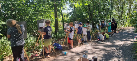 Kinder während der Ferienfreizeit an ihren Staffelleien.