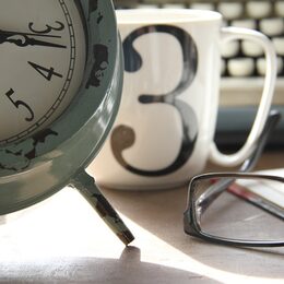 Foto mit Wecker, Kaffetasse, Brille und Tastatur