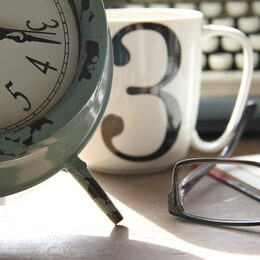 Uhr, Tasse, Brille auf einem Tisch