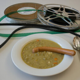 Zwei Filmrollen und eine Teller mit Erbsensuppe und Würstchen